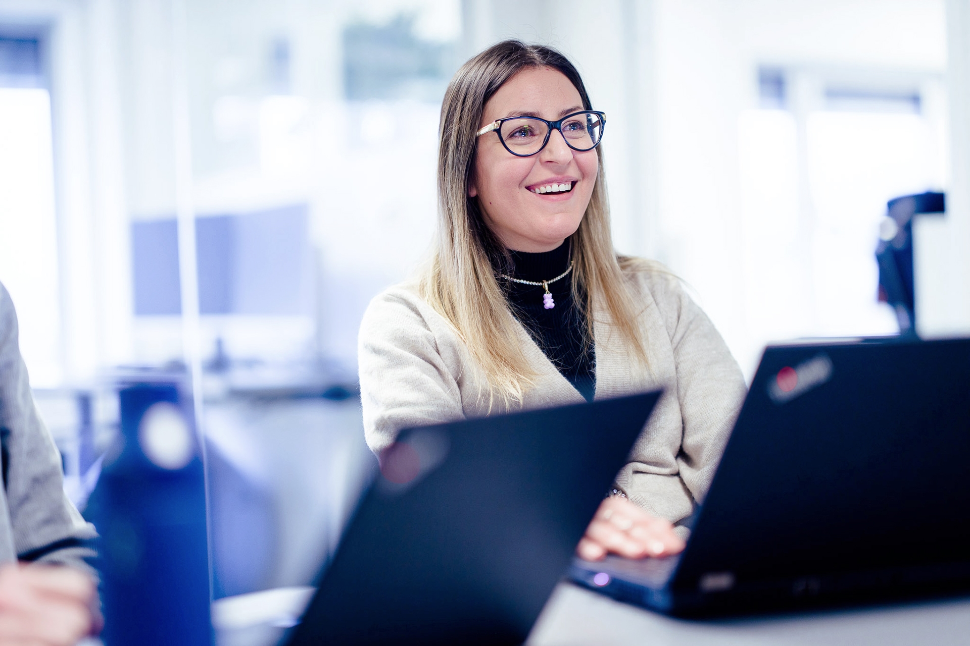 Image of a smilling woman sitting in front of the laptop to illustrate contact us page