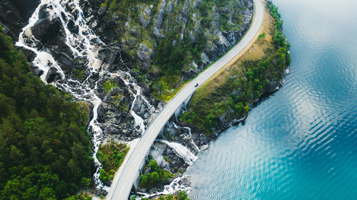 Road aerial view in between mountain and sea
