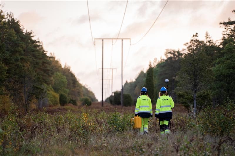 Two workers walk under the overhead grid